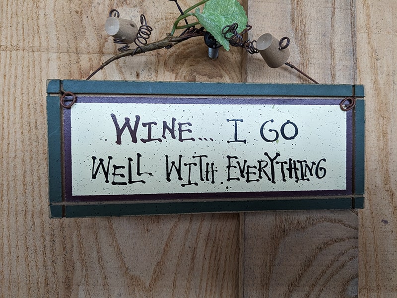 Image of a sign, “Wine…I go well with everything